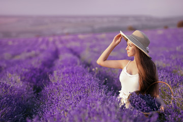 Beautiful young teen girl outdoors portrait. Brunette in hat with basket flowers harvesting in lavender field Provence, at sunset. Attractive pretty girl with long healthy curly hair.