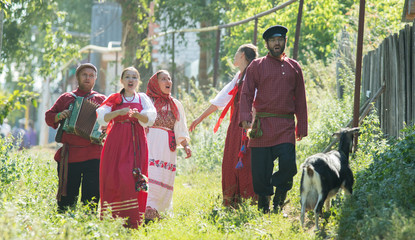 Wall Mural - Group of men and women in russian folk costumes in nature singing. Celebration