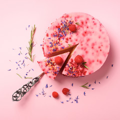 Delicious raspberry cake with fresh berries, rosemary and dry flowers on pink background. Copy space for your text. Vegetarian, vegan food concept