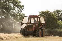 Tractor And Straw Baler In Wheat Field, Farmer Baling Straw.