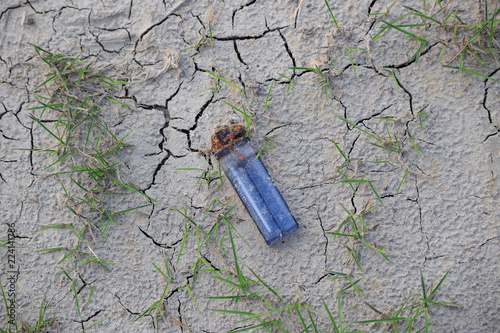 Fotografía Closeup of clear blue lighter with rusty flint in dry cracked soil