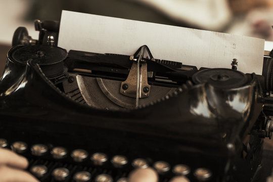Young man's hands typing on an antique vintage typewriter