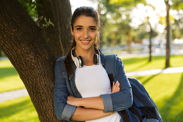 Poster - Young beautiful woman student walking in park looking camera.