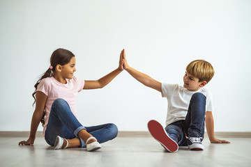 the happy boy and a girl sitting on the floor and gesturing