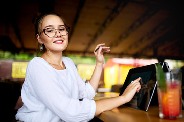 Fototapete - Digital artist finger touches convertible to 2 in 1 laptop display in tent mode and holds stylus. Mixed race multiethnic asian caucasian woman working on project design, writing notes on touchscreen.