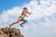 © Georgii - A boy is jumping from the cliff into the sea on a hot summer day. Holidays on the beach. The concept of active tourism and recreation