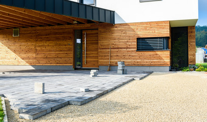 Laying gray concrete paving slabs in house courtyard driveway patio.