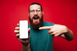 © Vulp - Amazed bearded man pointing at white screen on smartphone.
