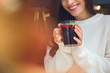 © LIGHTFIELD STUDIOS - cropped image of smiling woman holding cup of mulled wine at table in cafe