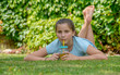 smiling teenager lying in the grass and drinking orange juice