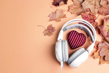 White Headphones With Red Knitted Heart, Autumn Maple Leaves And Copy Space. Top View, Flat Lay.