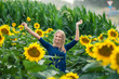 © miroslavrc - Happy blonde woman in sunflower field having fun.