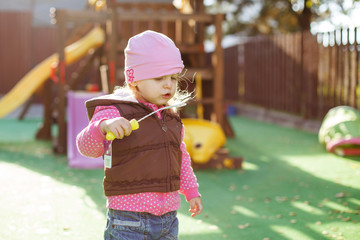 little girl blowing soap bubbles outdoor