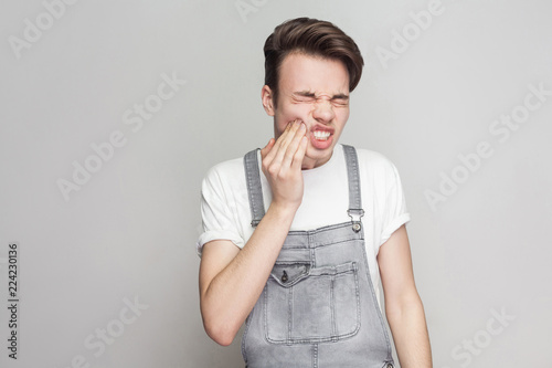 Foto Portrait of sadness teenager having severe toothache and touching and pressing fingers to cheek, closing eyes to relieve pain with helpless face