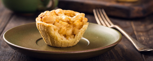 Homemade mini apple pie on green plate on wooden background. Healthy food concept. Banner.