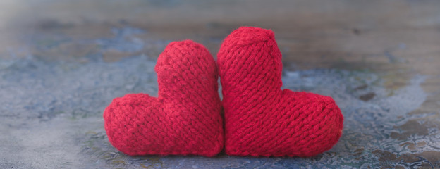 Wall Mural - Valentine's Day red knitted wool hearts on concrete background, banner