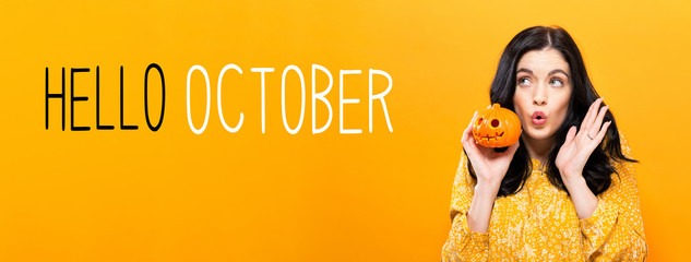 Hello October with young woman holding a pumpkin