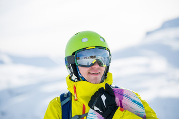 Photo of sportive man with snowboard against background of mountains