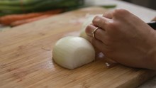 Hand With Engagement Ring Cutting An Onion On Wooden Cutting Board