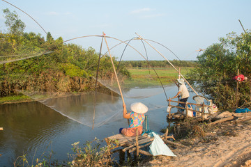  Nakhon Phanom, Thailand - 14 September 2018 : old woman catch fish with flattering on the rive