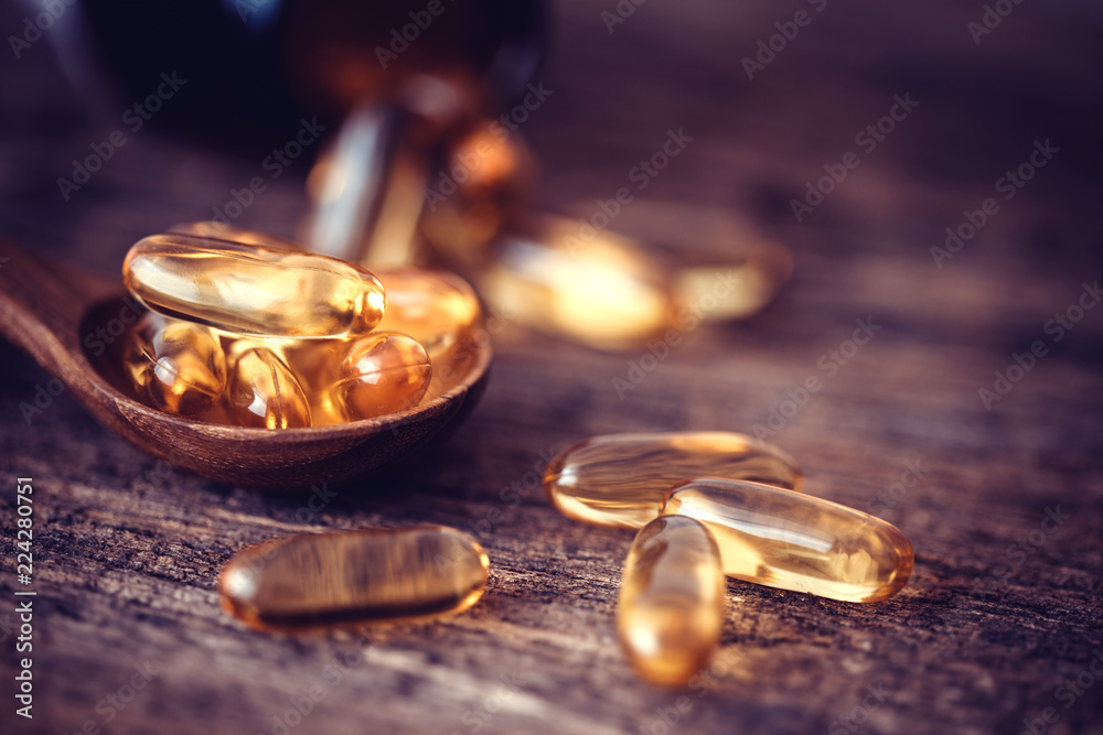 Obraz na płótnie Close up the vitamin D and Omega 3 fish oil capsules supplement on wooden plate for good brain , heart and health eating benefit w salonie