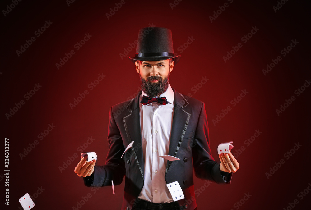 Magician showing tricks with cards on dark background