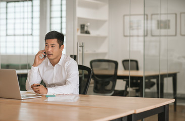 Young Asian businessman talking on his cellphone in an office