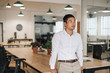 © mavoimages - Young Asian businessman standing in an office deep in thought