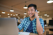 © mavoimages - Smiling Asian designer talking on a cellphone in an office