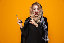 Magician Woman 20s Wearing Black Costume And Halloween Makeup Pointing Fingers Aside, Isolated Over Yellow Background