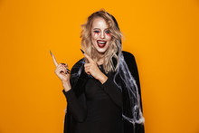 Young Woman 20s Wearing Black Costume And Halloween Makeup Pointing Fingers Aside, Isolated Over Yellow Background