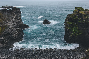 Wall Mural - aerial view of beautiful cliffs in front of blue ocean in Arnarstapi, Iceland on cloudy day