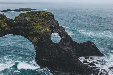 beautiful mossy cliff in front of blue ocean in Arnarstapi, Iceland