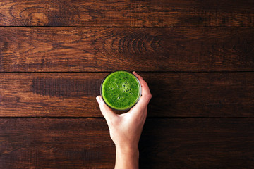 Smoothies, green drink in hand, diet food, wooden background, copy space