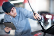 © zephyr_p - Young Asian auto mechanic holding digital tablet checking windshield wiper in auto service garage. Mechanical maintenance engineer working in automotive industry. Automobile servicing and repair
