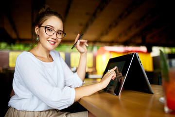 Fototapete - Digital artist finger touches convertible to 2 in 1 laptop display in tent mode and holds stylus. Mixed race multiethnic asian caucasian woman working on project design, writing notes on touchscreen.