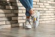 © New Africa - Woman in stylish sneakers near brick wall indoors, closeup