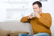 © auremar - man sat on sofa enjoying a hot drink