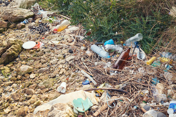 Wall Mural - Spilled garbage on the beach of the big city. Empty used dirty plastic bottles. Dirty sea sandy shore the Black Sea. Environmental pollution. Ecological problem. Bokeh moving waves in the background