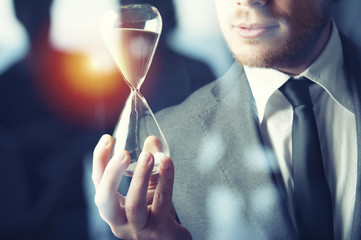 Businessman holding a hourglass. Concept of deadline in business