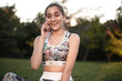 © Sunrise Team - Healthy excited surprised smiling beautiful brunette sports fitness slim woman in top with tropical print sitting outdoors in the park on grass with sundown light talking by mobile phone.