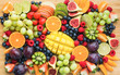Healthy raw fruits and berries platter background, strawberries raspberries oranges plums apples kiwis grapes blueberries, mango on the serving board, top view, selective focus