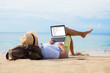 © Kaspars Grinvalds - Man reading email on laptop while relaxing on beach