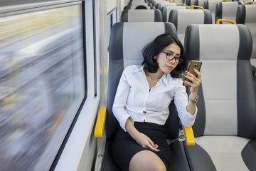 Young businesswoman holds phone in airport train