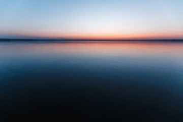 Wall Mural - Beautiful, pink violet dawn over the lake. Fog over the lake, the rays of the sun, very dense fog, dawn, the blue sky over the lake, the morning comes, the forest reflects in the water.