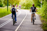 Fototapeta  - Cyclists ride on the bike path in the city Park 