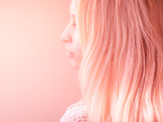 Beautiful pink hair on a pink pastel background, side view portrait