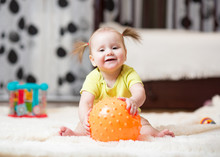Childhood And People Concept - Happy Baby Girl Playing With Ball On Floor At Home