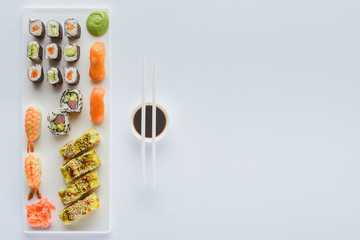 Wall Mural - top view of delicious sushi set and soy sauce in bowl with chopsticks isolated on white background