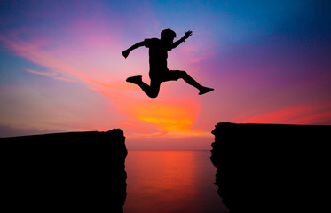 man jump over through on the gap of hill silhouette light, blue sky and sun on background.image for spirit and brave concept.spirit man is representative of success in the past and gold for the future